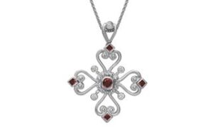 A silver cross-shaped pendant with intricate, swirling designs is adorned with red and clear gemstones. The pendant hangs from a delicate silver chain.