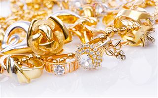 A collection of gold jewelry including rings, necklaces, and earrings, all adorned with various gemstones and intricate designs, displayed on a white background.