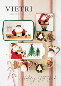 Assorted festive ceramic tableware featuring Santa Claus in various holiday activities, Christmas trees, gingerbread men, and candy canes, set on a striped cloth background. Text reads "VIETRI Irresistible Italian" at the top and "Holiday Gift Guide" at the bottom.