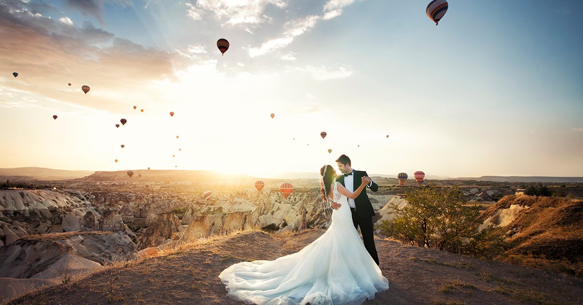Bride and groom dancing in front of a beautiful view of hot air balloons, celebrating in this year’s wedding season