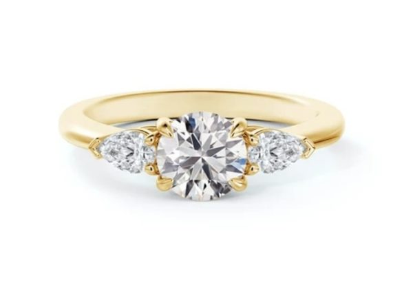 yellow gold engagement ring with a brilliant cut diamond center accented by two pear-shaped diamonds on each side
