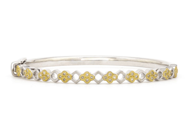 The Jude Frances Mixed Metal Open Kite Bangle showcases an intricate design of silver and yellow flower-shaped patterns adorned with small crystals, featuring a secure clasp lock for easy fastening around the wrist.