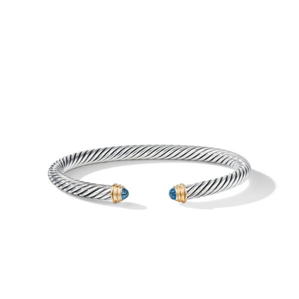 A silver and gold twisted cable bracelet with two blue gemstone caps at the open ends, each adorned with a gold band. The bracelet is slightly curved and set against a plain white background.