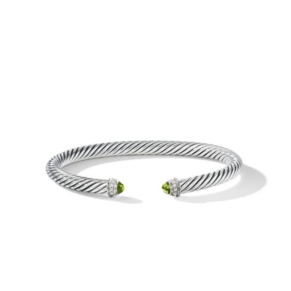 A silver twisted cable bracelet with open ends, adorned with small green gemstone caps and encircled by a row of diamonds at each end. The bracelet has a polished finish and rests on a white background.