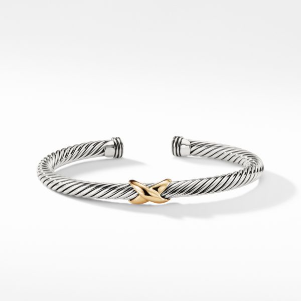 A silver-toned, twisted cuff bracelet with a central gold 'X' decoration. The clean, minimalist design showcases a contrast between the two metals, enhancing the bracelet's elegant and sophisticated look. The background is plain white.