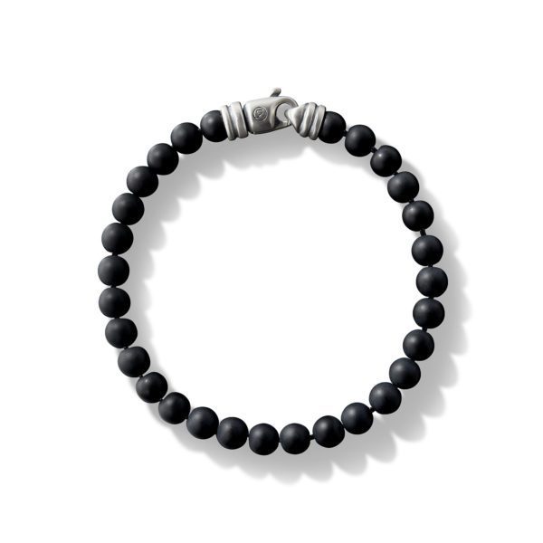 A beaded bracelet made of small, round, matte black beads, arranged in a circular pattern, with a metallic clasp that has a distinct ridged design. The bracelet is displayed on a plain white background.