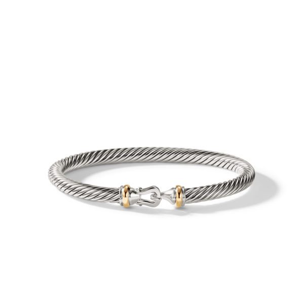 A sleek silver twisted cable bracelet with a clasp adorned by small gold accents on either side, creating a sophisticated two-tone design. The bracelet is simple yet elegant, making it suitable for various occasions.