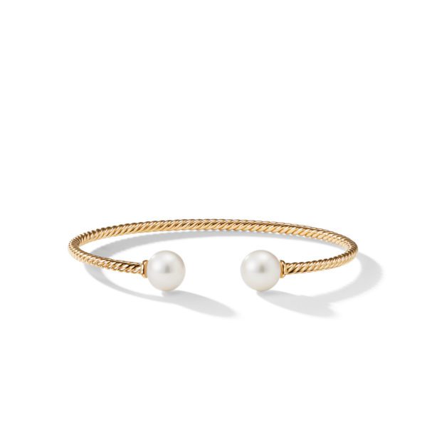 A gold twisted rope bangle bracelet with open ends is adorned with two large white pearls, one at each end. The bracelet is set against a neutral white background.