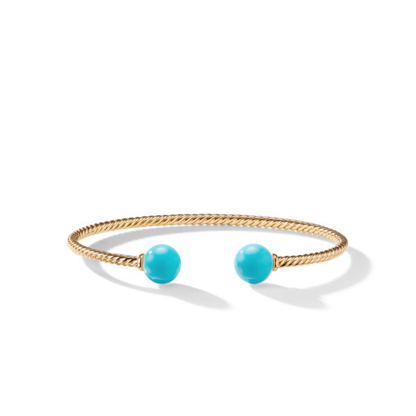 A gold twisted rope cuff bracelet featuring two turquoise beads at the open ends, placed on a white background.