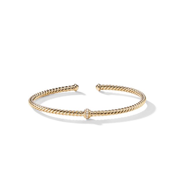 A twisted gold cuff bracelet with an open design, featuring a single central diamond-encrusted round accent. The bracelet's elegant and minimalist design is highlighted against a plain white background.