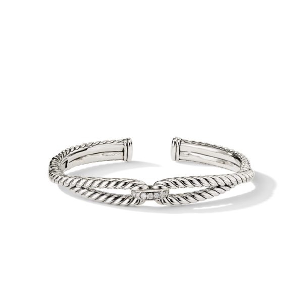 An elegant silver cuff bracelet featuring twisted rope-like design elements with a small cluster of diamonds in the center. The open-ended design showcases polished and intricate details, casting a subtle shadow on the surface underneath.