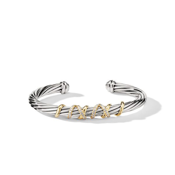 A twisted silver cuff bracelet with three gold X-shaped embellishments, each studded with small diamonds. The bracelet's texture features intricate ridges, and it is open on one side, forming a slight curve. The overall design is elegant and sophisticated.