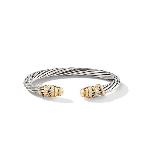 A twisted silver cable cuff bracelet with two gold-capped ends, each adorned with diamond accents in an X pattern. The bracelet's open design allows for easy wearing and adjustment. The piece is elegantly crafted with a mix of silver, gold, and diamonds.