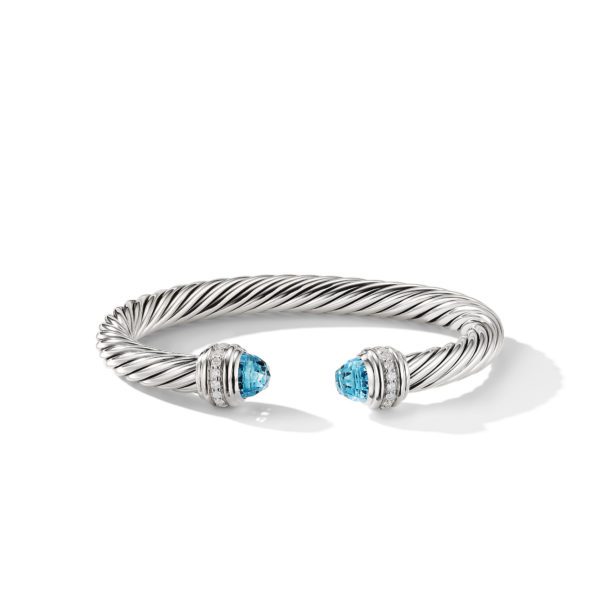 A silver twisted cable cuff bracelet featuring two blue gemstone end caps, each encircled by small ridged silver and smooth silver bands. The bracelet is open-ended and has a sleek, polished appearance.