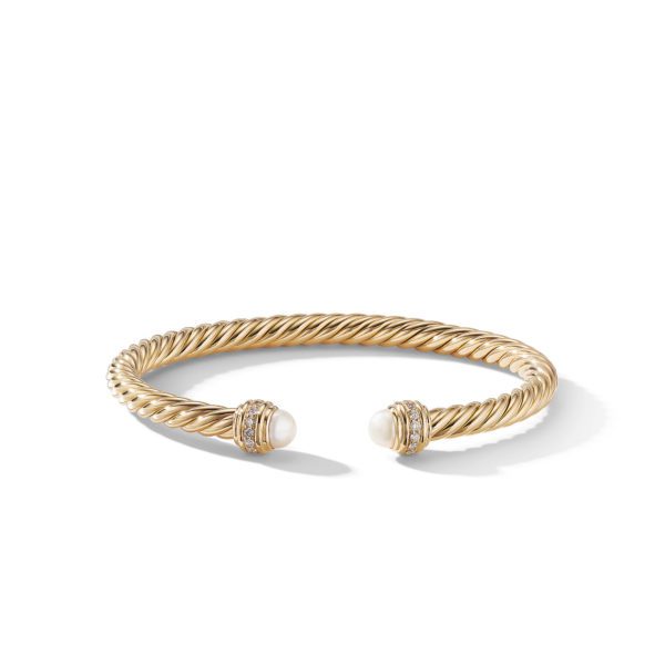 A twisted gold bangle bracelet with open ends, each adorned with a white pearl. The bracelet has a polished finish and the pearls are encircled by small, decorative gold accents. The bangle is displayed against a plain white background.