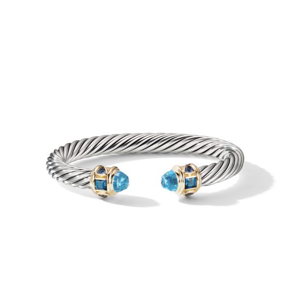 A twisted metal bracelet with an open-ended design. The ends are decorated with blue gemstones, each set in a gold frame. The bracelet has a sleek, sculptural look with a combination of silver and gold tones.