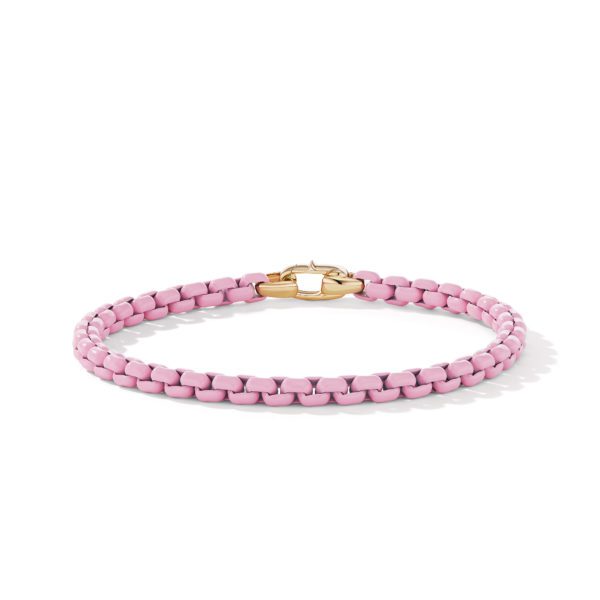 A pink woven bracelet with a gold clasp. The simple yet elegant design highlights the intricate weaving of the pink material, which contrasts nicely with the polished gold clasp. The bracelet is displayed on a white background.