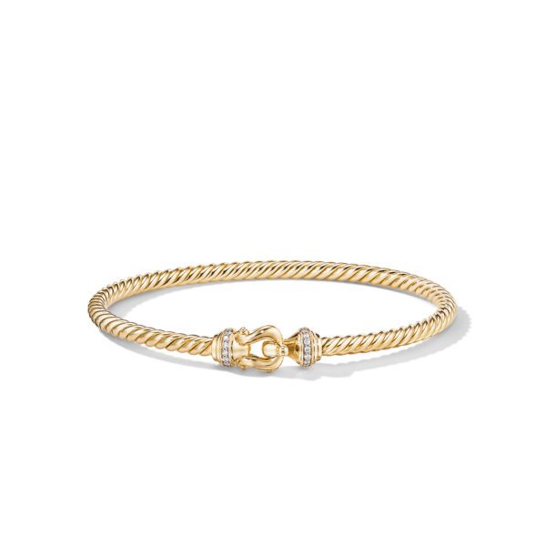 A gold bracelet featuring a twisted rope design with a sleek, circular clasp in the center adorned with small white gemstones. The bracelet has a luxurious and elegant appearance.