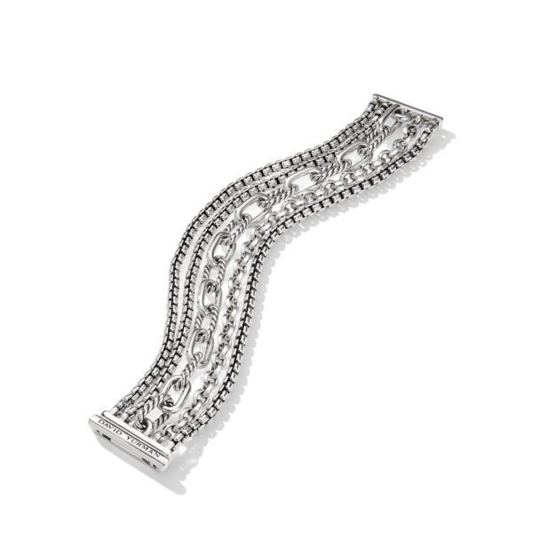 A silver bracelet with a mix of various interlinked chain styles, draped in an elegant, wave-like curve. The bracelet has a rectangular clasp that features an engraved brand name. The overall design is intricate and polished, reflecting light softly.