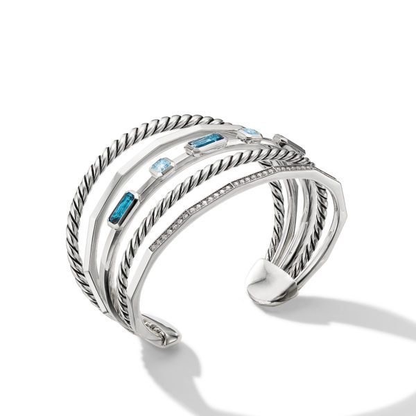 A stylish, open-ended silver cuff bracelet featuring multiple twisted bands adorned with rectangular and square blue gemstones. The design has a modern and elegant look, with a sophisticated blend of textures and colors. The bracelet casts a subtle shadow on a white background.