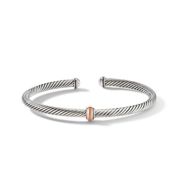 A silver twisted wire cuff bracelet with a sleek, open-ended design. The bracelet features subtle ridges and has a rose-gold accent at the center, creating a striking two-tone look. It rests on a plain white background, casting a soft shadow.