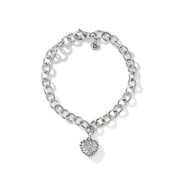 A silver chain bracelet featuring interlocking circular links. The bracelet has a lobster clasp and a small circular charm near the clasp. A textured, heart-shaped pendant hangs prominently from the center of the bracelet. The background is plain white.