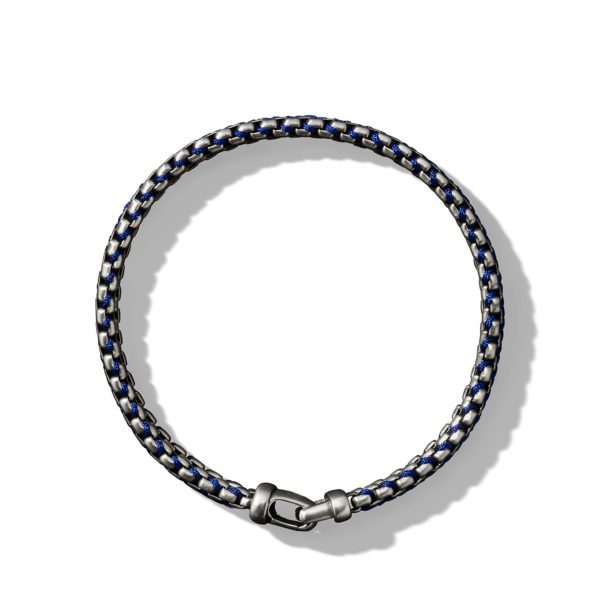 A close-up of a round, woven bracelet featuring blue and white interlaced threads with metallic accents. The bracelet is fully closed with a silver clasp and is centered on a plain white background.