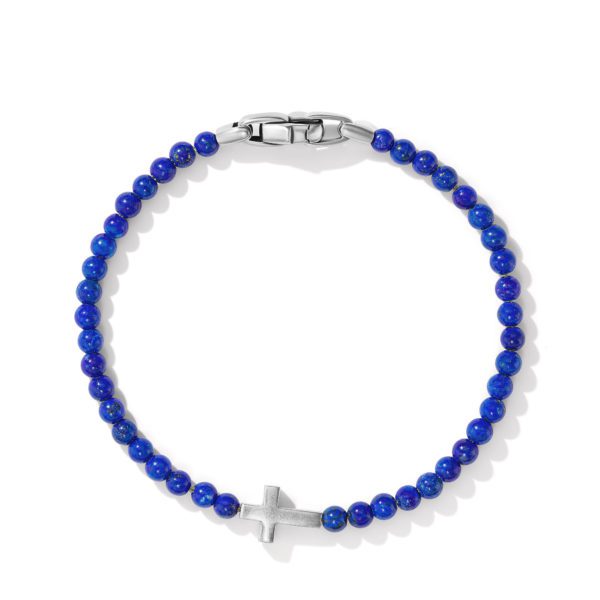 A delicate bracelet with deep blue spherical beads and a metal clasp. The bracelet features a silver cross charm at its center.