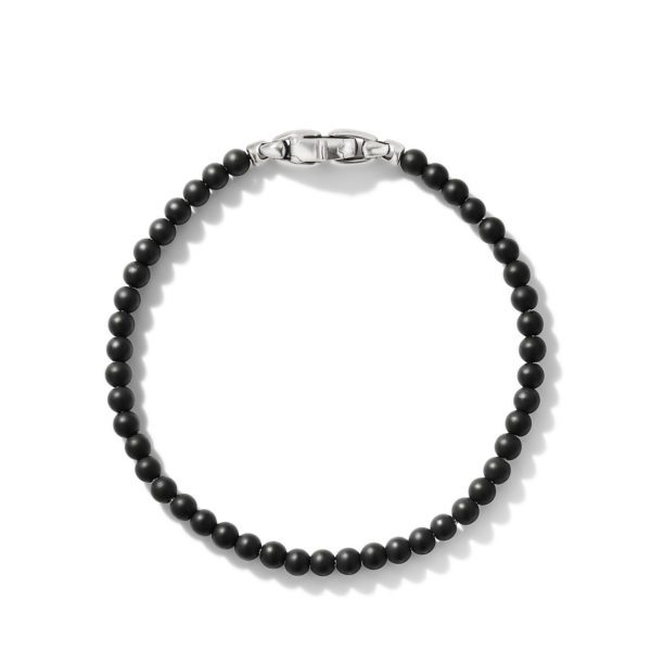 A minimalist bracelet featuring a string of small, round, matte black beads with a sleek silver clasp. The beads are uniformly sized, and the clasp has a polished metal finish that contrasts with the dark beads.