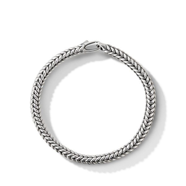 A close-up image of a silver chain bracelet with a herringbone pattern. The intricate, tightly-woven design showcases the sleek and polished metal surface, giving it an elegant and refined appearance.