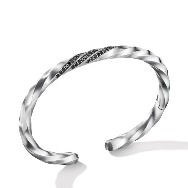 A sleek, open-ended silver cuff bracelet with a twisted design. The bracelet features a diagonal section adorned with small black jewels, adding a touch of elegance and contrast to its polished finish.