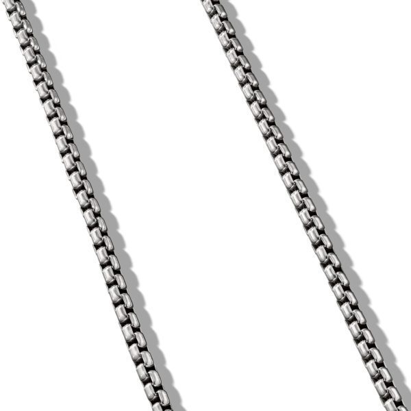 A close-up of a silver chain necklace against a white background. The chain consists of rectangular links arranged in a uniform pattern, casting shadows to the right.