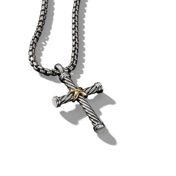 A close-up image of a metal chain necklace featuring a cross pendant. The cross is designed to resemble two nails bound together with a small gold-colored wire at the intersection. The background is a plain white surface, and the pendant casts a shadow.