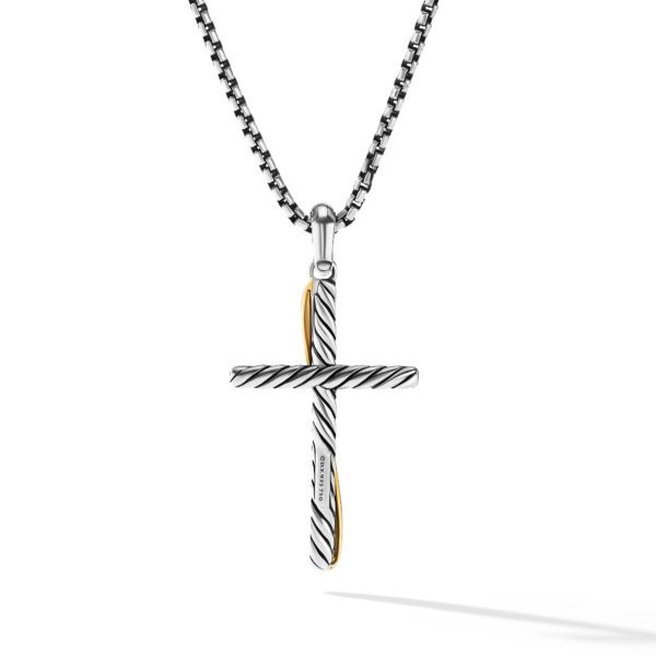 A close-up image of a silver cross pendant with diagonal grooves, suspended from a silver chain. The cross has a small gold accent on one side and casts a shadow on a plain white background.