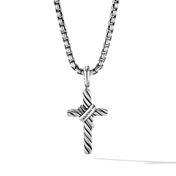 A silver pendant necklace featuring a textured cross with a small, diagonal inscribed band. The cross pendant has a twisted design and hangs from a sturdy chain with box-shaped links, casting a subtle shadow.