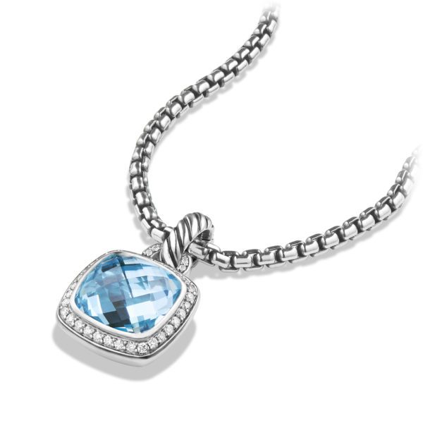 A silver necklace featuring a square pendant set with a large, faceted blue gemstone. The gemstone is framed by a border of small, clear crystals. The chain has a box pattern, and the pendant's bail is twisted, adding a decorative touch to the elegant design.