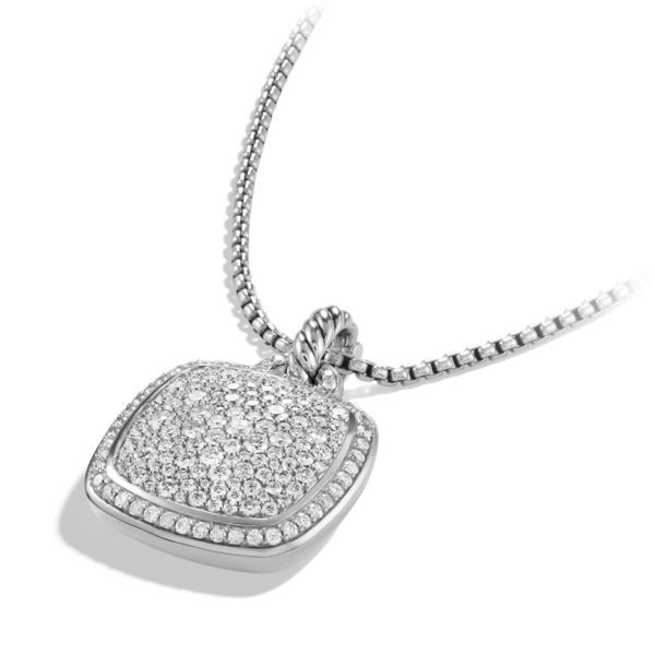 A silver necklace with a box chain features a square pendant encrusted with multiple small, sparkling diamonds, creating a shimmering effect. The pendant has a slightly rounded design with a decorative bail connecting it to the chain.