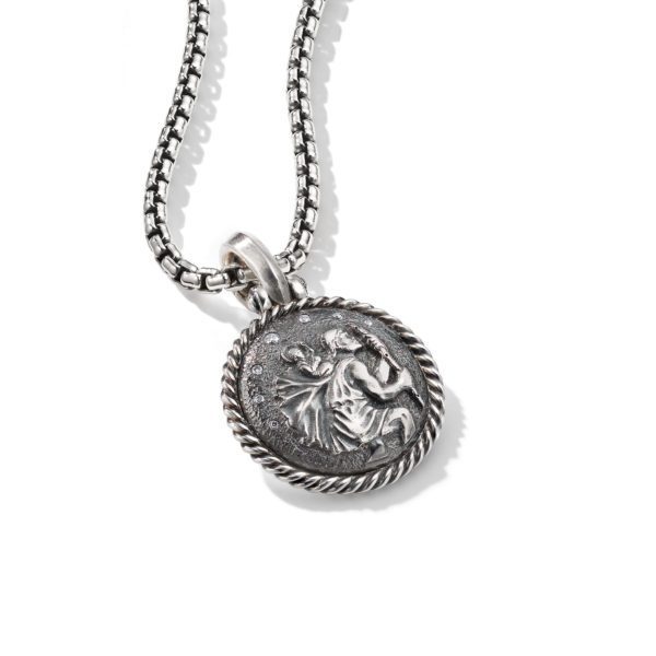 A silver necklace with a round pendant is shown. The pendant features an engraved design of a classical figure, possibly ancient Greek or Roman, wrapped in flowing robes. The pendant's edge is framed with a twisted rope pattern.