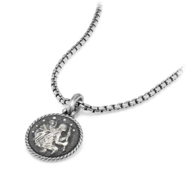 A silver necklace featuring a circular pendant with an engraved design. The pendant, which has a textured edge, depicts a figure carrying another person on its back. The chain has a box link structure, adding a modern touch to the intricate pendant.