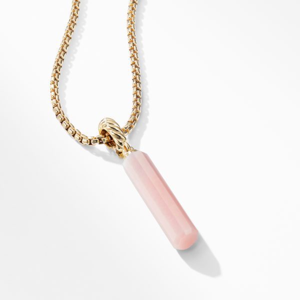 A gold chain necklace with a pendant made of a pink cylindrical crystal. The crystal has a smooth, faceted surface and is capped with a gold loop through which the chain passes. The background is white and minimalistic, highlighting the necklace's elegance.