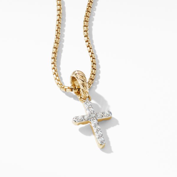 A close-up of a gold necklace featuring a pendant in the shape of a cross. The cross is encrusted with small, sparkling gemstones and hangs from a gold chain with a box link design. The background is plain white, highlighting the details of the jewelry.