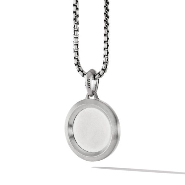 A silver-toned circular pendant with a minimalist design hangs on a chain with a box link pattern. The pendant is smooth, with no apparent engravings or embellishments, and casts a soft shadow on a white background.