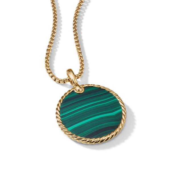 A gold necklace features a round malachite pendant with green and dark green stripes encased in a gold rope-like border. The pendant hangs from a gold chain against a white background.