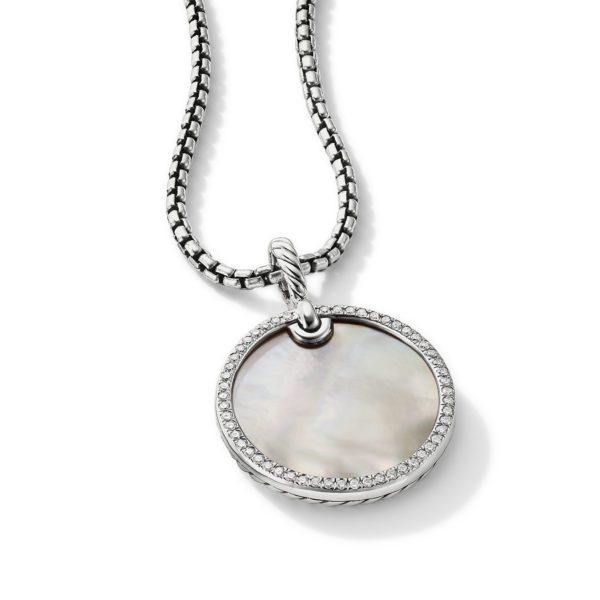 A silver pendant necklace featuring a round, iridescent mother-of-pearl inlay framed by a border of small sparkling stones. The pendant hangs from a silver chain with a woven design. The necklace is photographed against a plain white background.