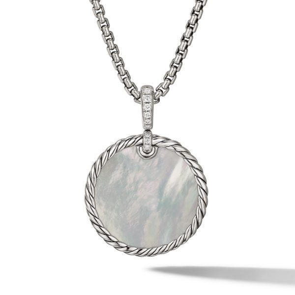 A silver necklace featuring a round pendant with a mother-of-pearl center, bordered with a twisted rope design. The pendant is attached to a sturdy, silver chain through a bail embellished with small, sparkling gems.