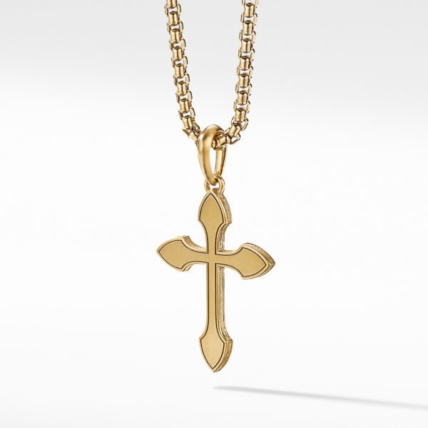 A gold cross pendant with a polished finish hangs from a gold chain with interlinked patterns. The cross features pointed tips and a sleek, elegant design. The background is a simple, light gradient that emphasizes the pendant and chain.