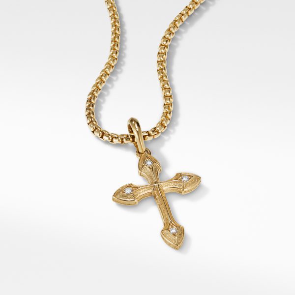 A gold chain necklace with a gold cross pendant. The cross features intricate detailing and small diamond-like stones at the points, all set against a plain white background.