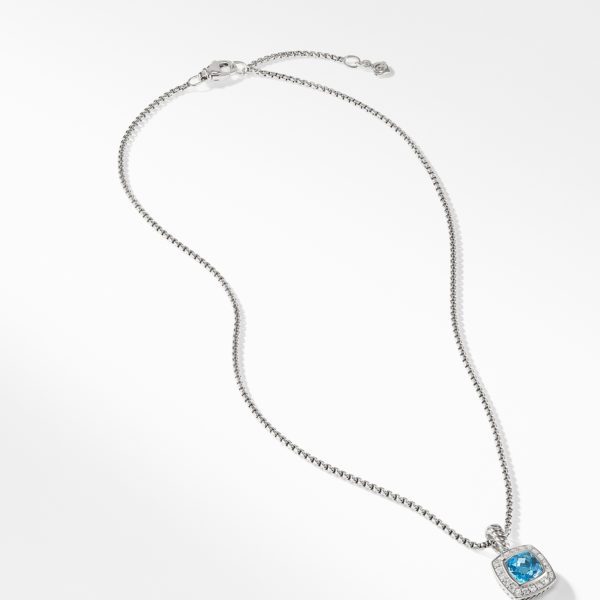 A delicate silver necklace with a small square pendant featuring a blue gemstone. The pendant has a sparkly border and is connected to a thin silver chain that includes an adjustable clasp. The overall design is elegant and minimalist.