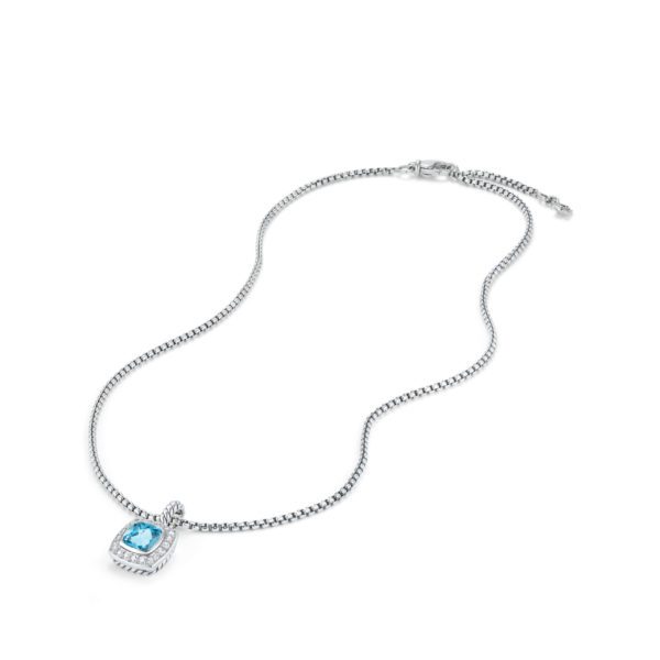 A silver necklace with a box chain featuring a blue gemstone pendant set in a detailed square frame. The pendant is centrally positioned, with the necklace unclasped and laid out flat on a white background.