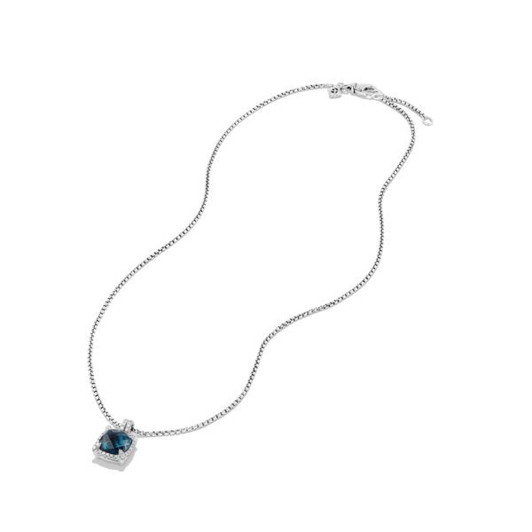 A silver necklace featuring a square pendant with a blue gemstone in the center. The pendant is surrounded by small clear stones. The chain is thin and delicate, with a simple clasp at the top. The necklace is laid out against a white background.